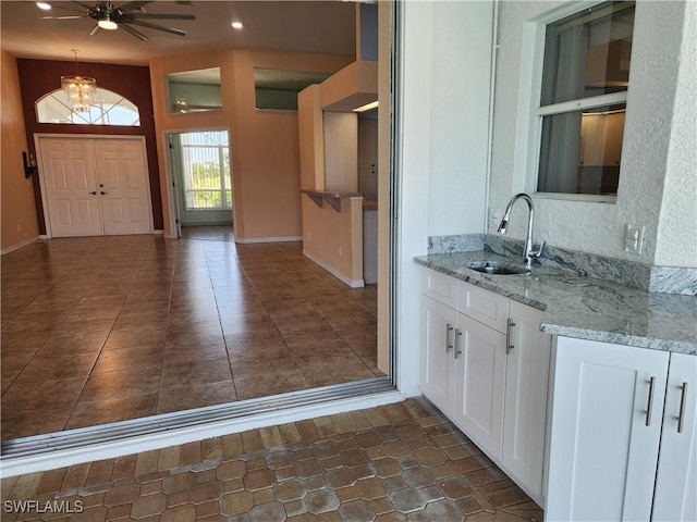 kitchen with open shelves, a sink, recessed lighting, white cabinetry, and light stone counters
