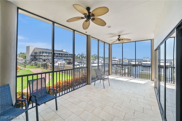 unfurnished sunroom with ceiling fan and a water view