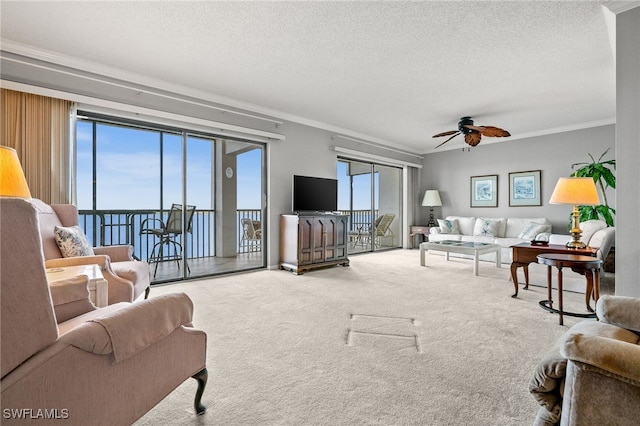 living room with crown molding, ceiling fan, carpet floors, and a textured ceiling