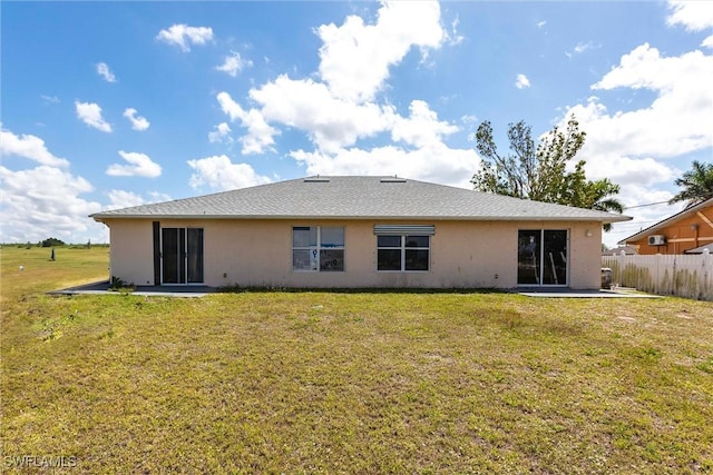 rear view of house with a patio, stucco siding, fence, and a yard