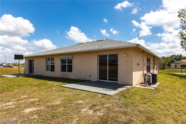 back of house featuring a lawn, central AC, stucco siding, a shingled roof, and a patio area