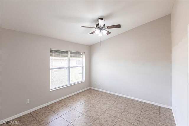 spare room with baseboards, light tile patterned floors, and a ceiling fan