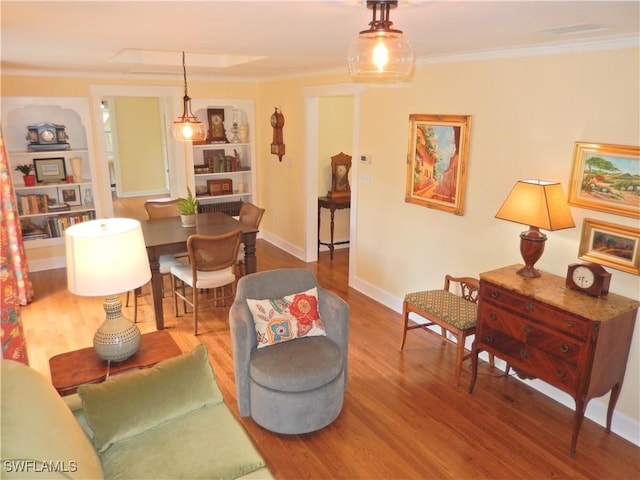 living area with crown molding, baseboards, built in shelves, and wood finished floors