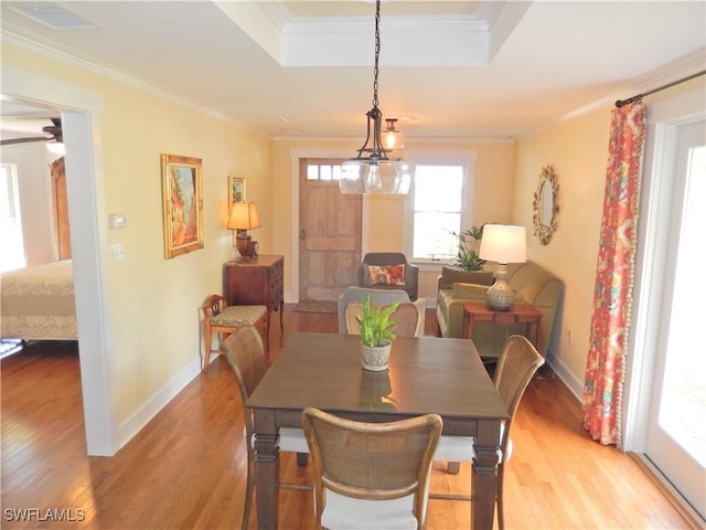 dining area with light wood-type flooring, crown molding, and a wealth of natural light