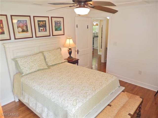 bedroom with crown molding, baseboards, a ceiling fan, and wood finished floors