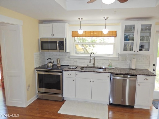 kitchen with a sink, dark stone counters, stainless steel appliances, and white cabinetry