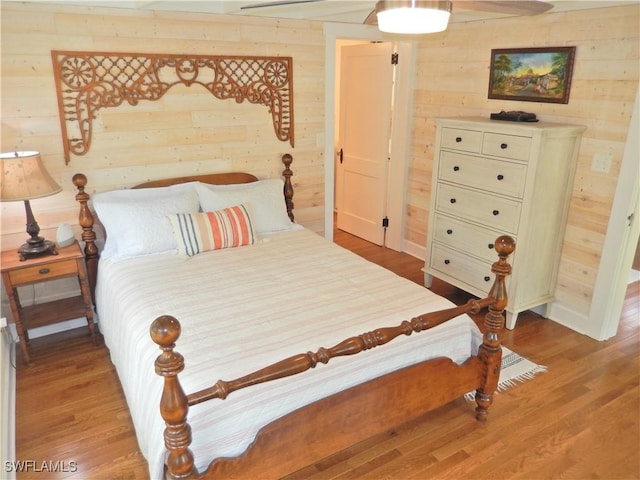 bedroom featuring light wood-style floors and wood walls