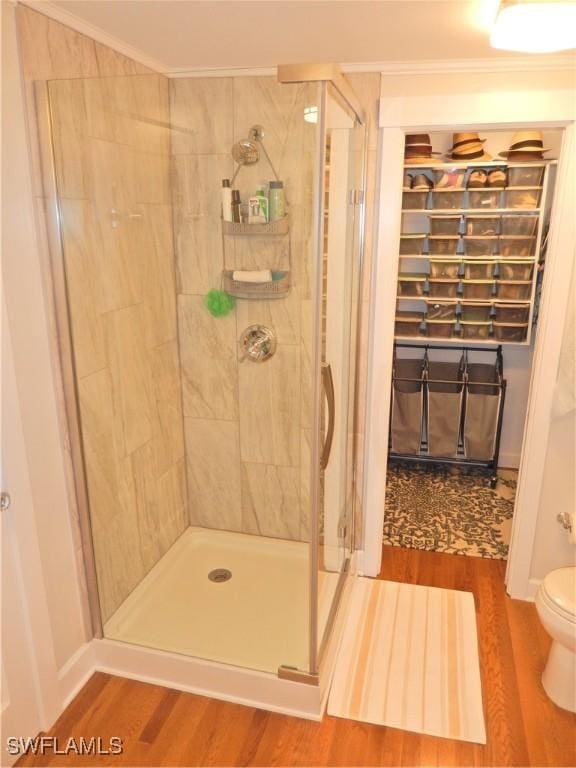 full bath with crown molding, toilet, a shower stall, and wood finished floors