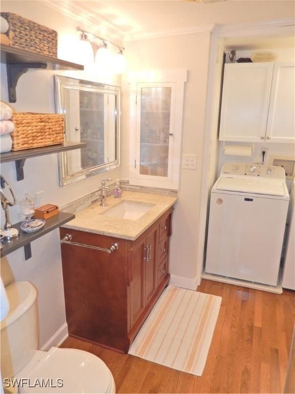 bathroom featuring crown molding, wood finished floors, baseboards, toilet, and washer / dryer