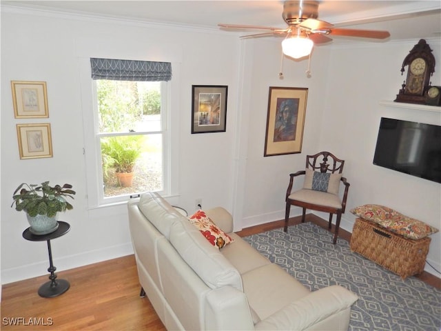 living area featuring crown molding, baseboards, ceiling fan, and wood finished floors