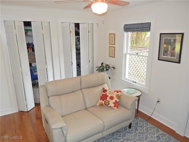 living area featuring crown molding, a ceiling fan, baseboards, and wood finished floors
