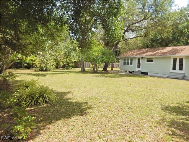 view of yard featuring fence, french doors, and entry steps