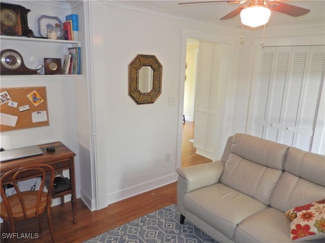 living area with crown molding, a ceiling fan, baseboards, and wood finished floors