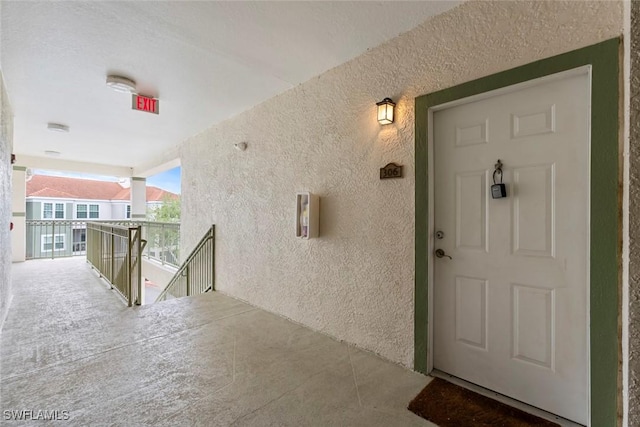 view of exterior entry with a balcony and stucco siding