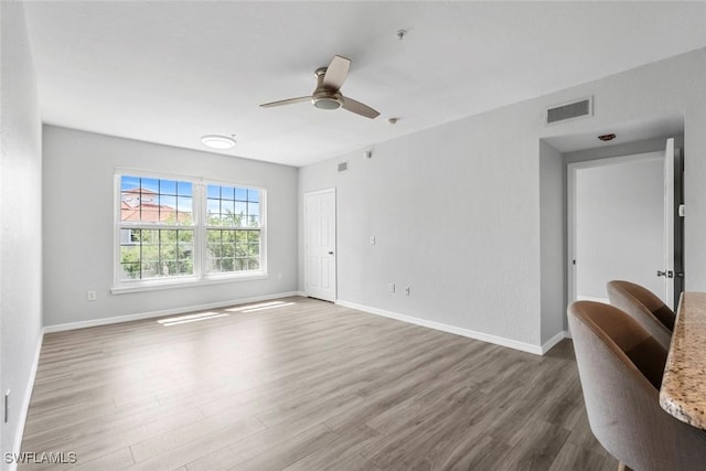 unfurnished room featuring a ceiling fan, wood finished floors, baseboards, and visible vents