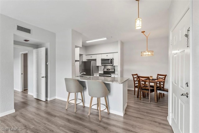 kitchen with white cabinetry, visible vents, stainless steel appliances, and light wood-type flooring