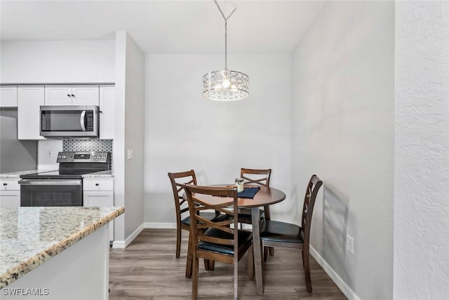 dining area featuring a notable chandelier, baseboards, and light wood finished floors