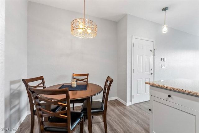 dining space with baseboards, a notable chandelier, and light wood-type flooring