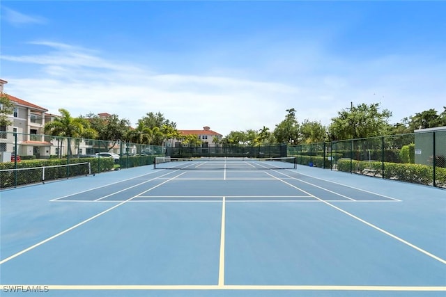 view of tennis court with community basketball court and fence
