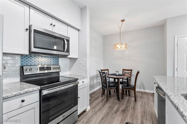 kitchen featuring a chandelier, light wood finished floors, tasteful backsplash, appliances with stainless steel finishes, and white cabinetry