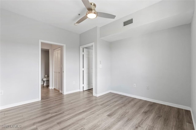 spare room with baseboards, visible vents, light wood-style floors, and a ceiling fan