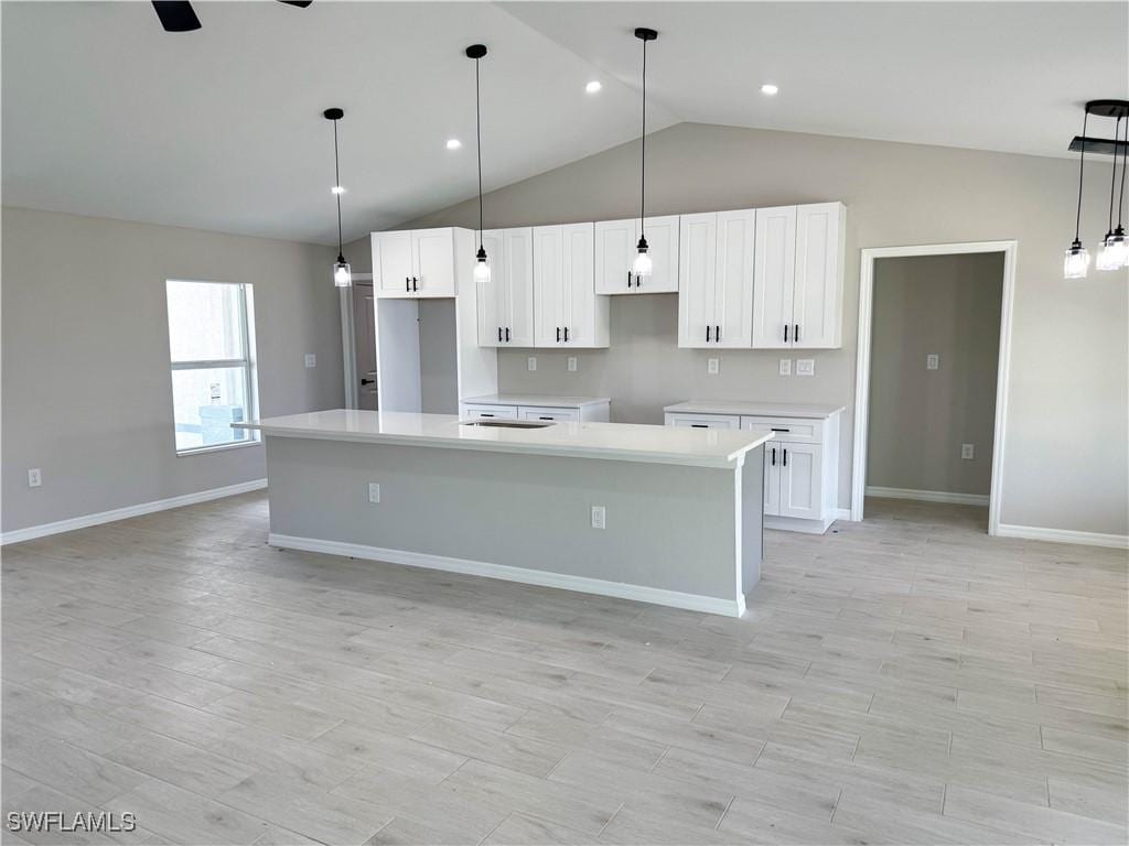 1806 NE 27th St, Cape Coral, FL 33909 - kitchen featuring white cabinetry, light wood-style flooring, a center island, and light countertops