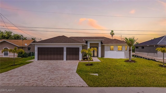 309 SW 15th Ter, Cape Coral, FL 33991 - view of front of house with stucco siding, an attached garage, a front lawn, and decorative driveway