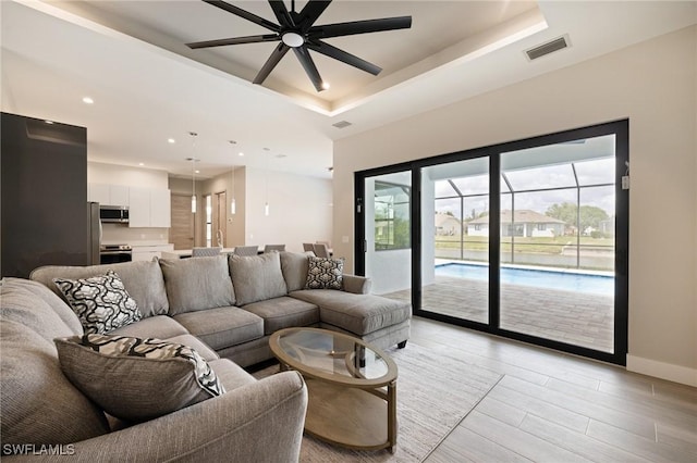 309 SW 15th Ter, Cape Coral, FL 33991 - living area featuring a ceiling fan, a tray ceiling, baseboards, and visible vents