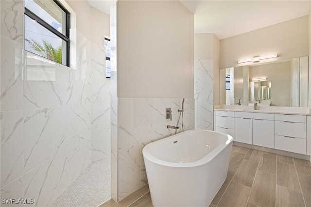 309 SW 15th Ter, Cape Coral, FL 33991 - bathroom featuring tile walls, a freestanding bath, vanity, and a marble finish shower