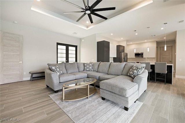 309 SW 15th Ter, Cape Coral, FL 33991 - living area featuring a raised ceiling, wood finish floors, baseboards, and ceiling fan