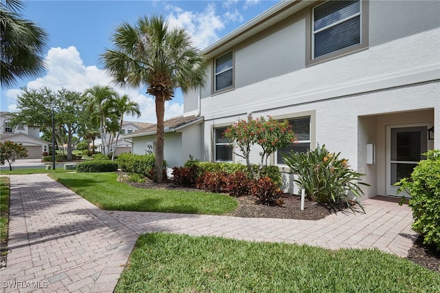 view of side of home with stucco siding and a lawn