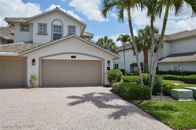 view of front of property featuring a garage, stucco siding, a tiled roof, and decorative driveway