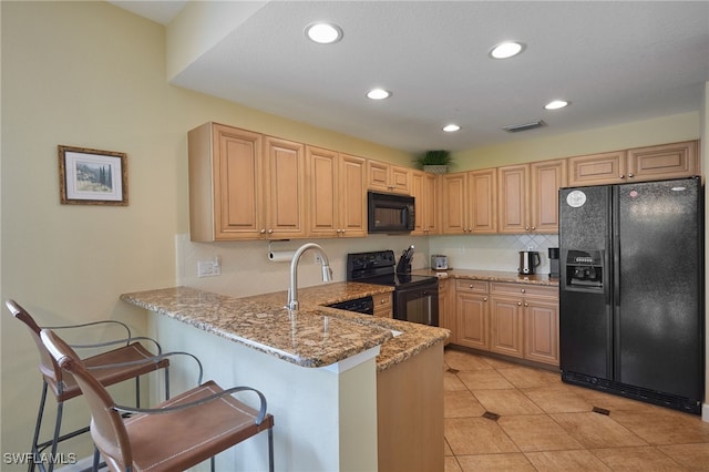 kitchen featuring light stone countertops, visible vents, light brown cabinets, and black appliances