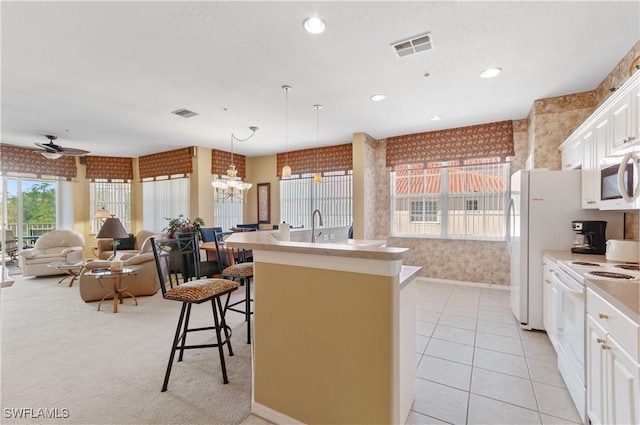 4834 Hampshire Ct Unit 207, Naples, FL 34112 - kitchen with a breakfast bar, white appliances, open floor plan, white cabinetry, and visible vents