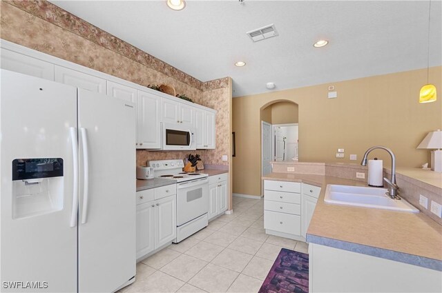4834 Hampshire Ct Unit 207, Naples, FL 34112 - kitchen with white appliances, arched walkways, visible vents, light tile patterned flooring, and a sink