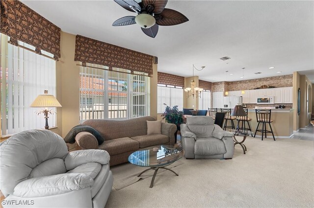 4834 Hampshire Ct Unit 207, Naples, FL 34112 - living room with light carpet, visible vents, and ceiling fan with notable chandelier