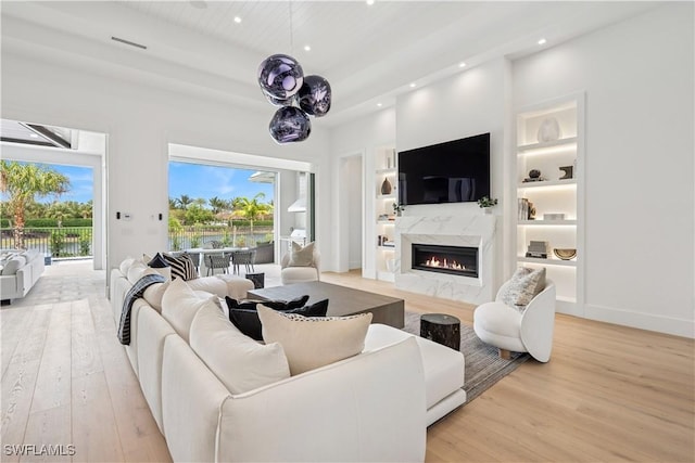 3359 Fanny Bay Ln N, Naples, FL 34114 - living room with light wood-type flooring, a high end fireplace, recessed lighting, built in features, and a water view