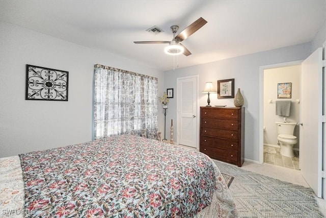 bedroom featuring visible vents, a ceiling fan, ensuite bath, and light carpet
