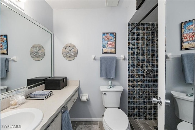 bathroom with a shower stall, vanity, baseboards, and toilet