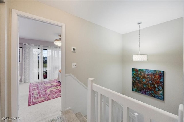 hall featuring an upstairs landing and carpet