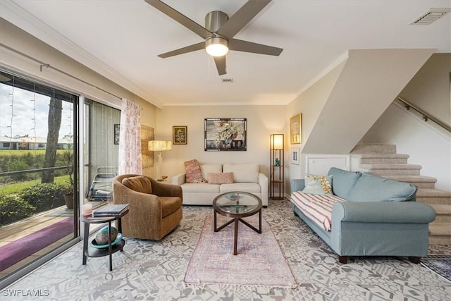 living room with ceiling fan, ornamental molding, visible vents, and stairs