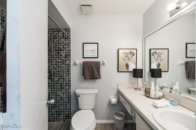 full bathroom featuring vanity, baseboards, toilet, tiled shower, and visible vents