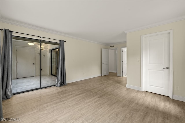 spare room featuring crown molding, baseboards, and light wood-type flooring