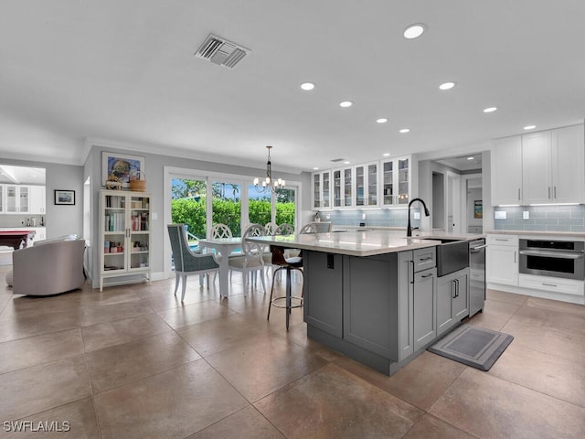 kitchen featuring white cabinets, a notable chandelier, a sink, stainless steel appliances, and visible vents