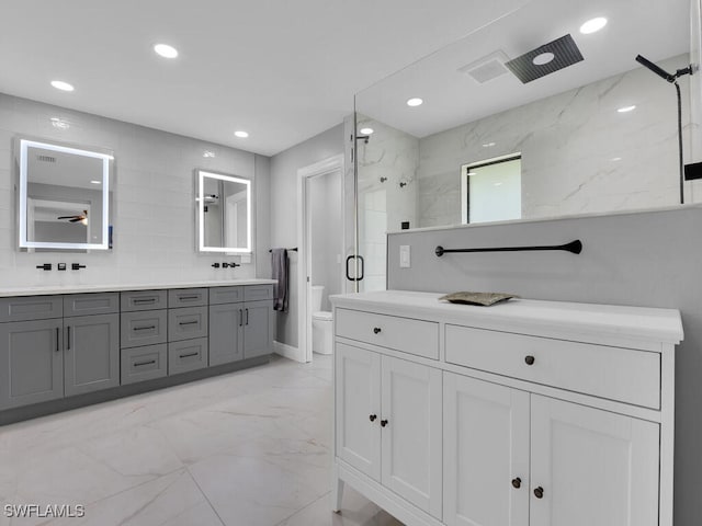 bathroom with double vanity, toilet, marble finish floor, a marble finish shower, and recessed lighting