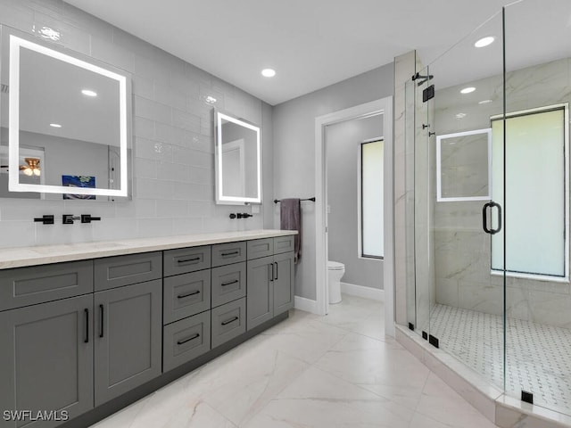 bathroom with double vanity, toilet, marble finish floor, baseboards, and a shower stall
