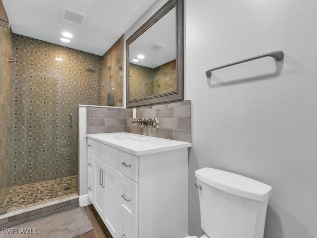 bathroom featuring backsplash, visible vents, a stall shower, vanity, and toilet