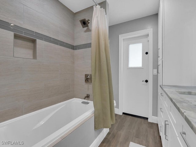 bathroom with shower / bath combo with shower curtain, baseboards, wood finished floors, and vanity