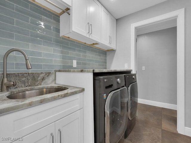 laundry area featuring baseboards, a sink, cabinet space, and washer and dryer