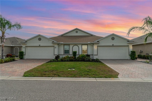 ranch-style house featuring a garage, driveway, and a lawn